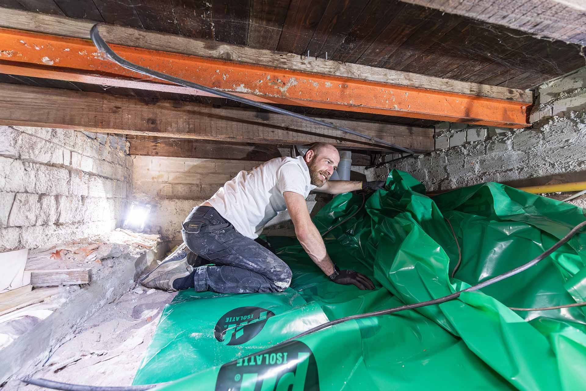 Bodemfolie wordt geplaatst in een kruipruimte voor bodemisolatie