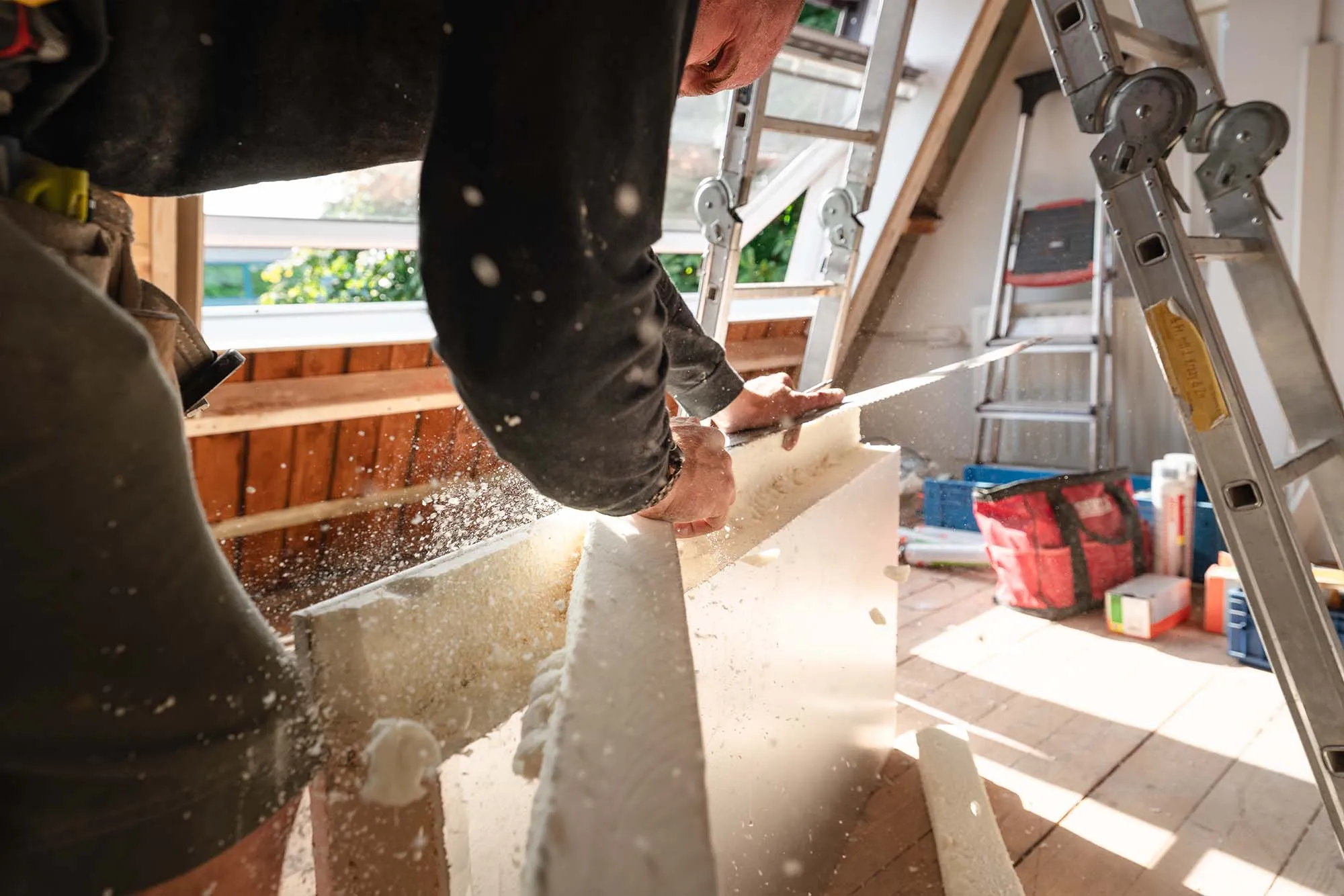 Monteur zaagt een isolatieplaat op maat voor het dak van een woning in Haarlem